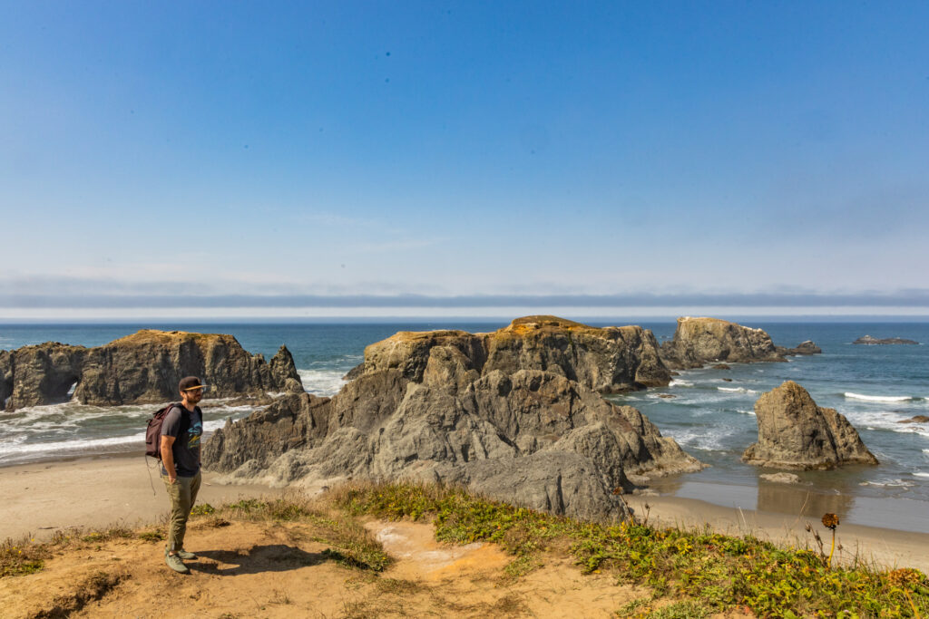 A man stands in front of a rocky beach at Coquille Point in Bandon, Oregon.