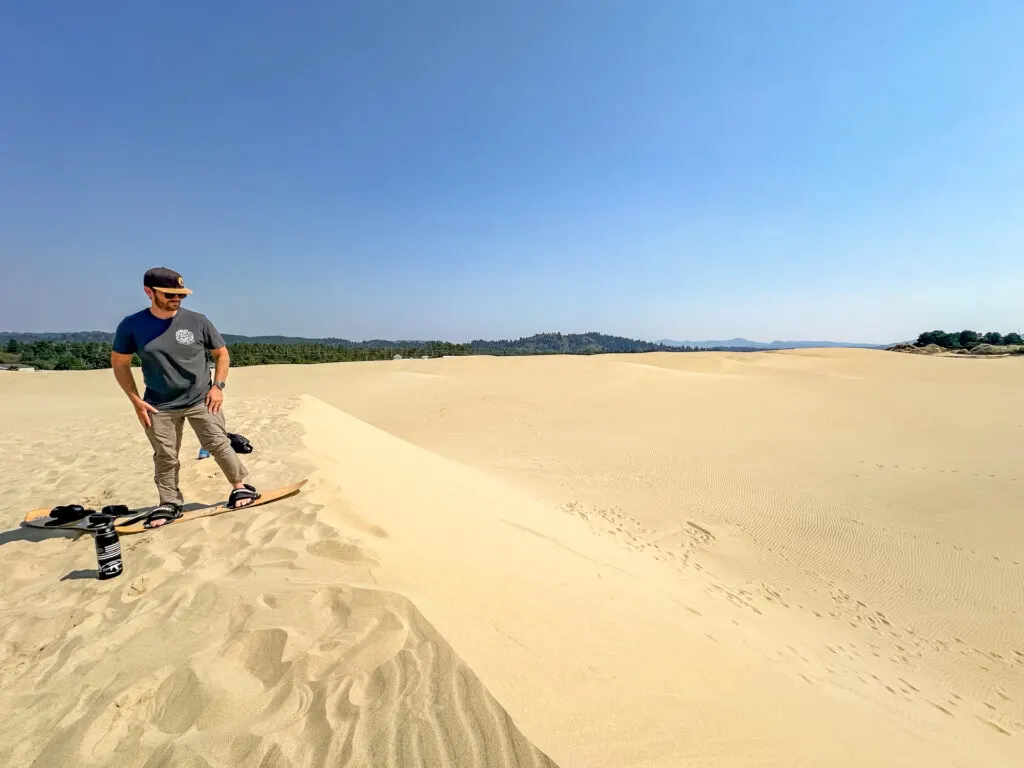 A man Sandboarding at Sand Master Park in Florence, OR.