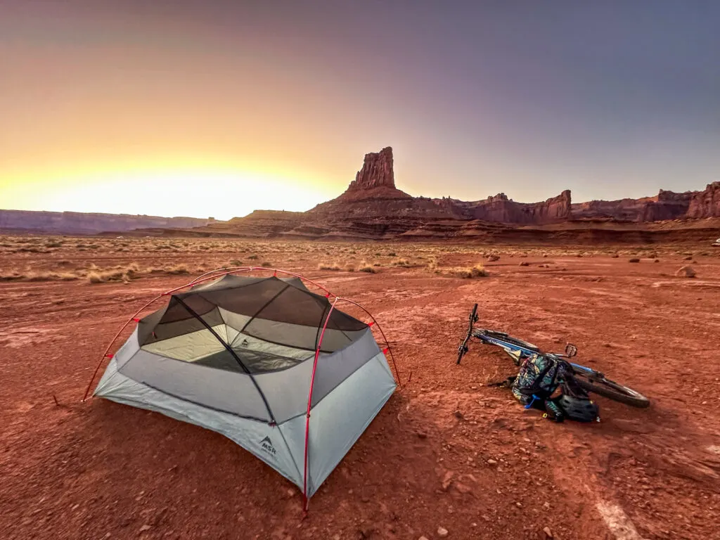 Bikepacking White Rim Trail: A bike laying next to an MSR tent at a backcountry campsite in Canyonlands National Park.