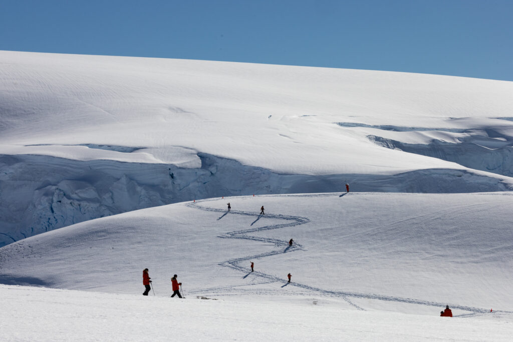 Antarctica expedition cruise passengers hiking up switchbacks in the snow.