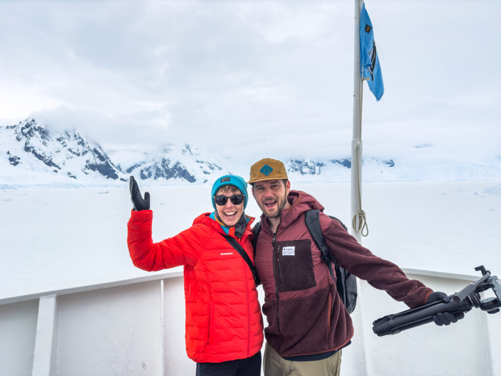 A man and woman smile from the deck of an Antarctica expedition cruise.