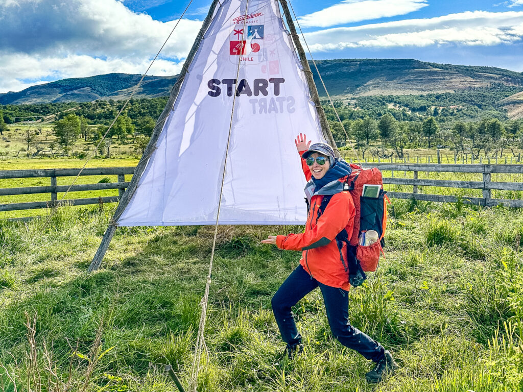 A woman poses excitedly in front of the starting line.