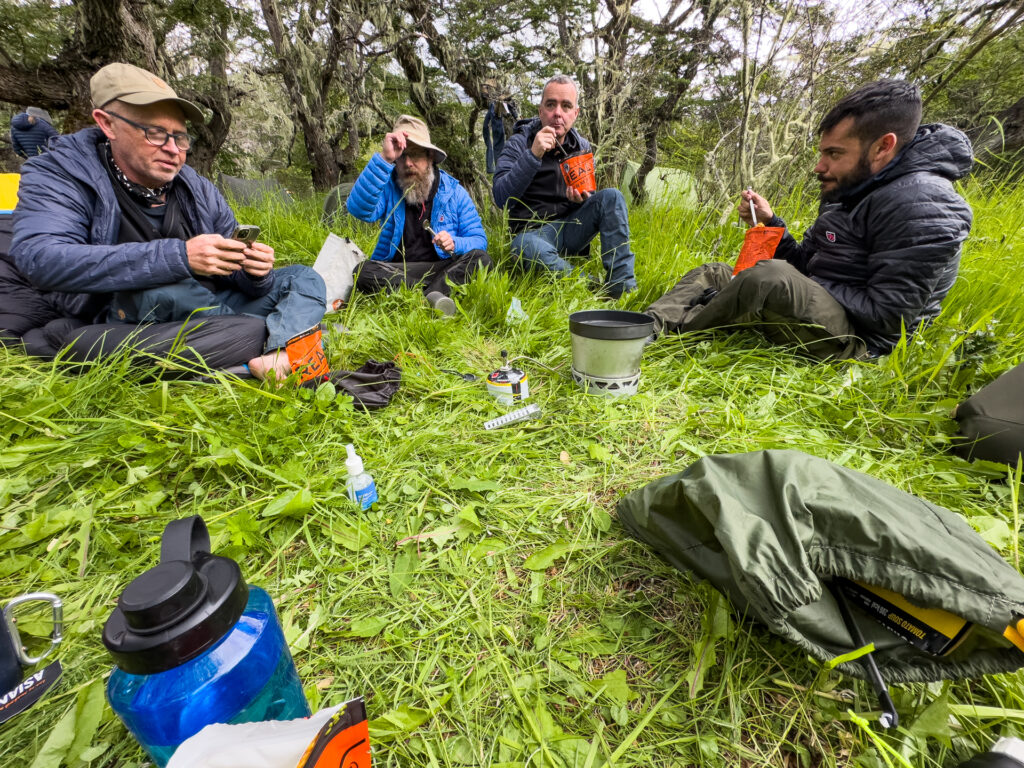 Four men sit together eating dinner out of bags.