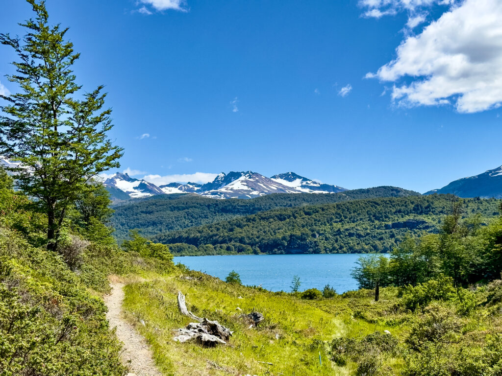 A lake in front of mountains and a hiking trail in Patagonia.