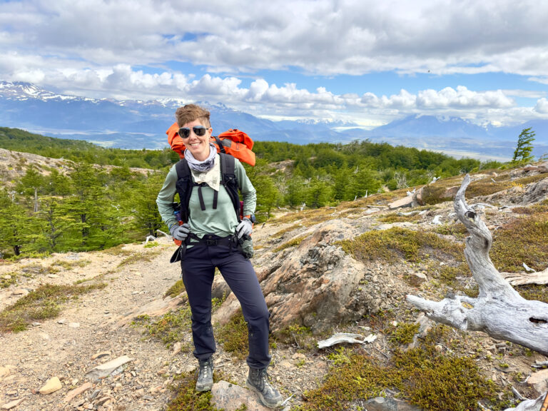 A woman stands with a backpack in the mountains in Patagonia.