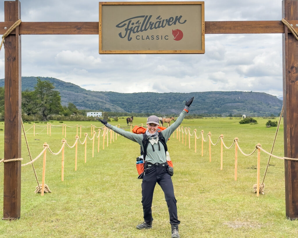 A woman poses excitedly under the finish line at Fjällräven Classic Chile.