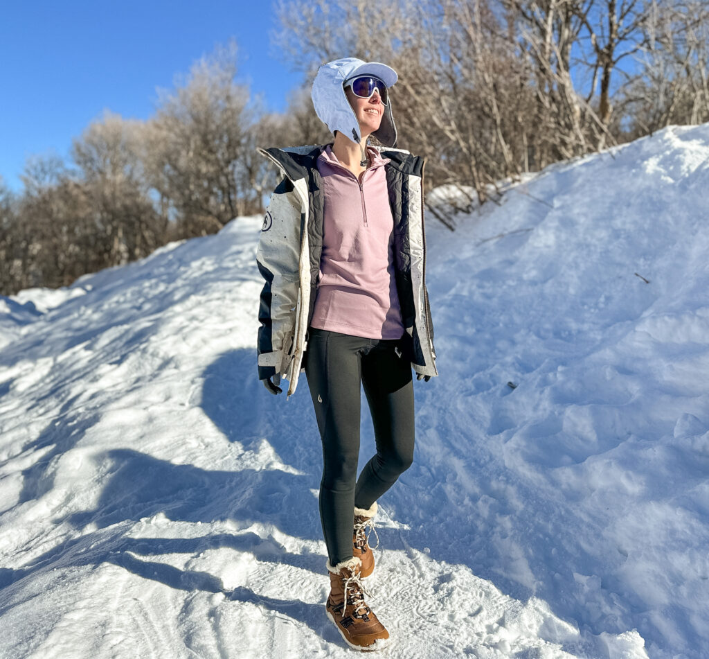 A woman hiking in the snow wearing Gnara Go Free Leggings.