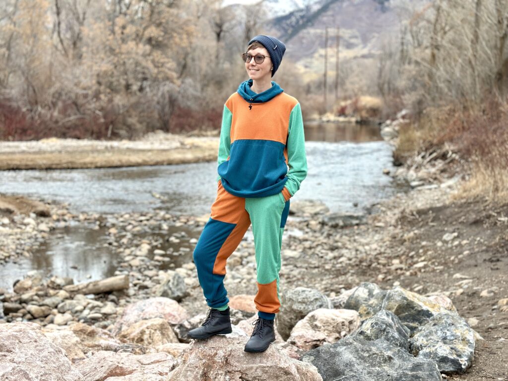 A woman stands in front of a river in a matching custom Sambob grid fleece hoodie and pants.