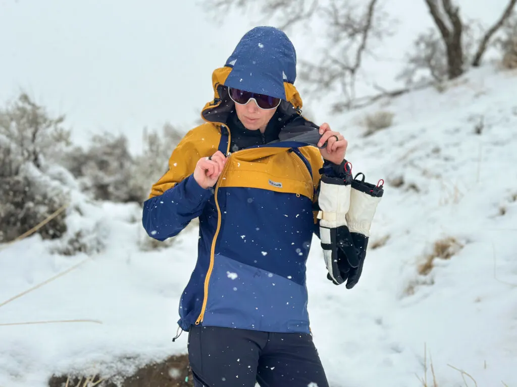 A woman unzips one side of the Paramo Hybrid Smock from the top down.