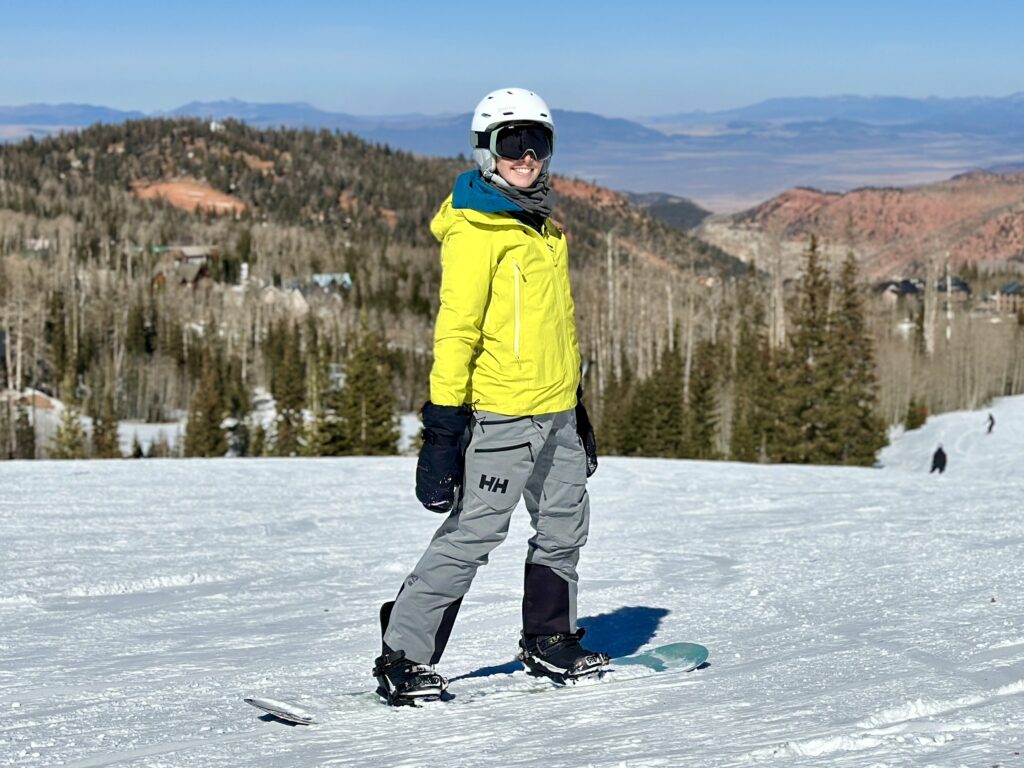 A female snowboarder wears a Helly Hansen Verglas Infinity Shell jacket and Elevation Infinity Shell Bibs.