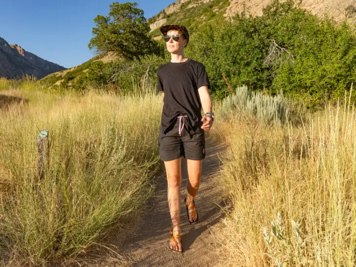 A woman hiking in the late afternoon sun wearing a t-shirt and hiking shorts for women.