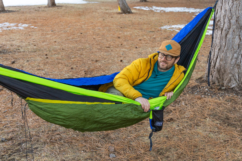 A man hangs in an Eno two-person hammock with an underquilt.