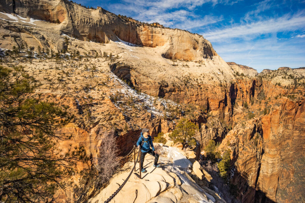 A woman stands on a narrow path on Angel's Landing in Zion National Park.