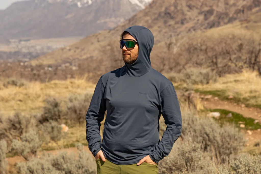 A man wears the Marmot Arex sun hoodie with the hood up.