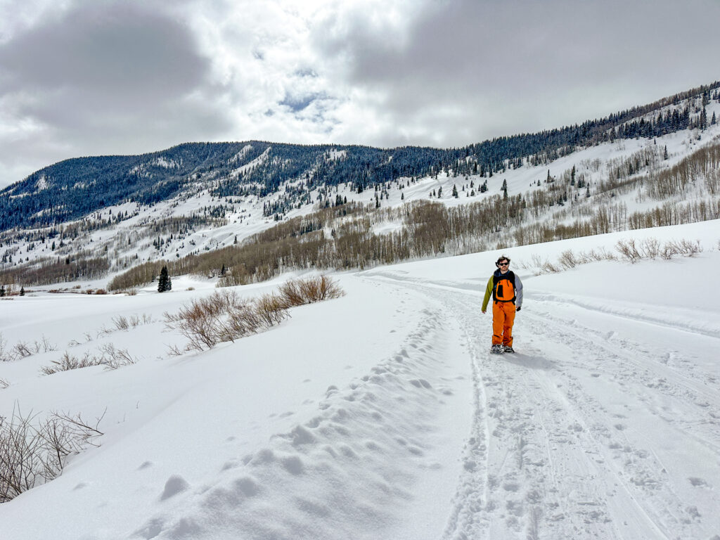 Things to do in Crested Butte in Winter: A man snowshoes on the road out to RMBL.