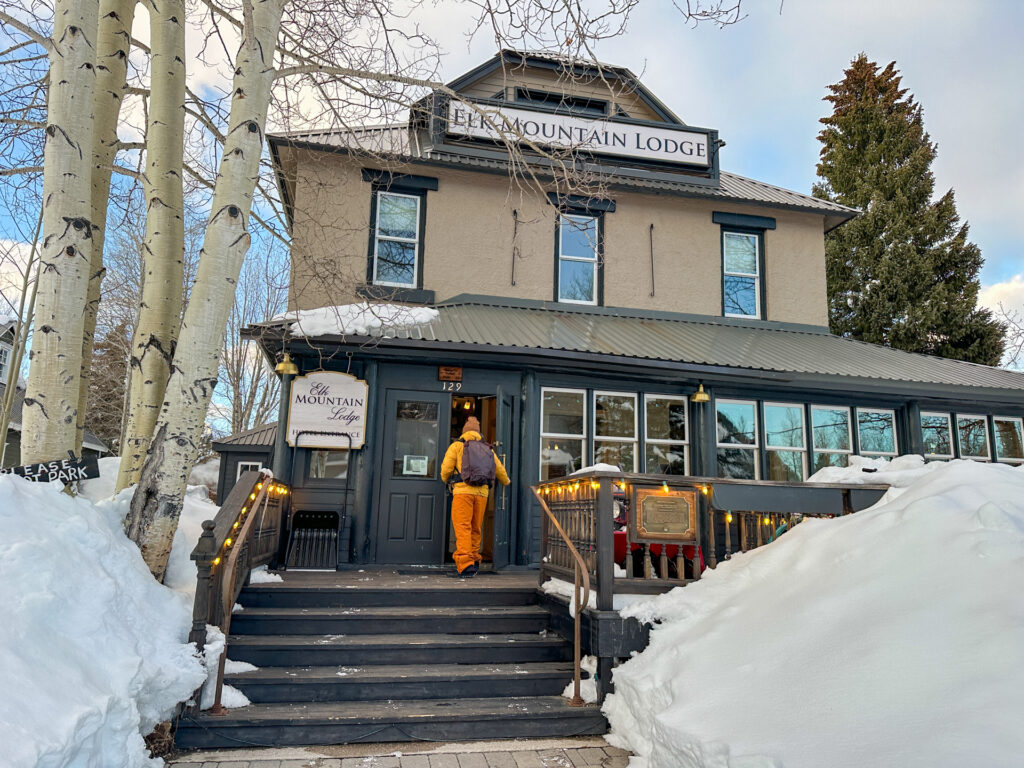 A man in snow gear enters Elk Mountain Lodge in Crested Butte, Colorado in the winter.