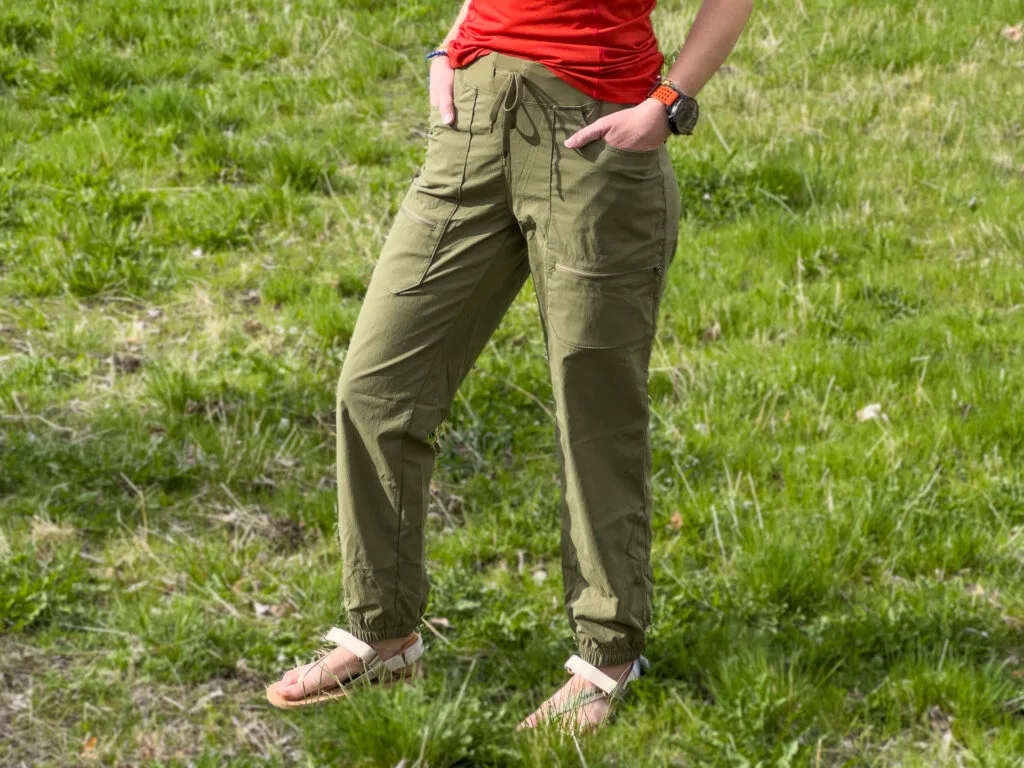 A woman's lower half wearing the Patagonia Quandary Joggers as she stands on a grassy trail.