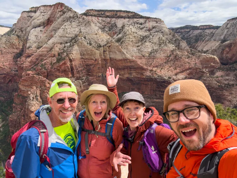 Four people pose smiling at Zion National Park.
