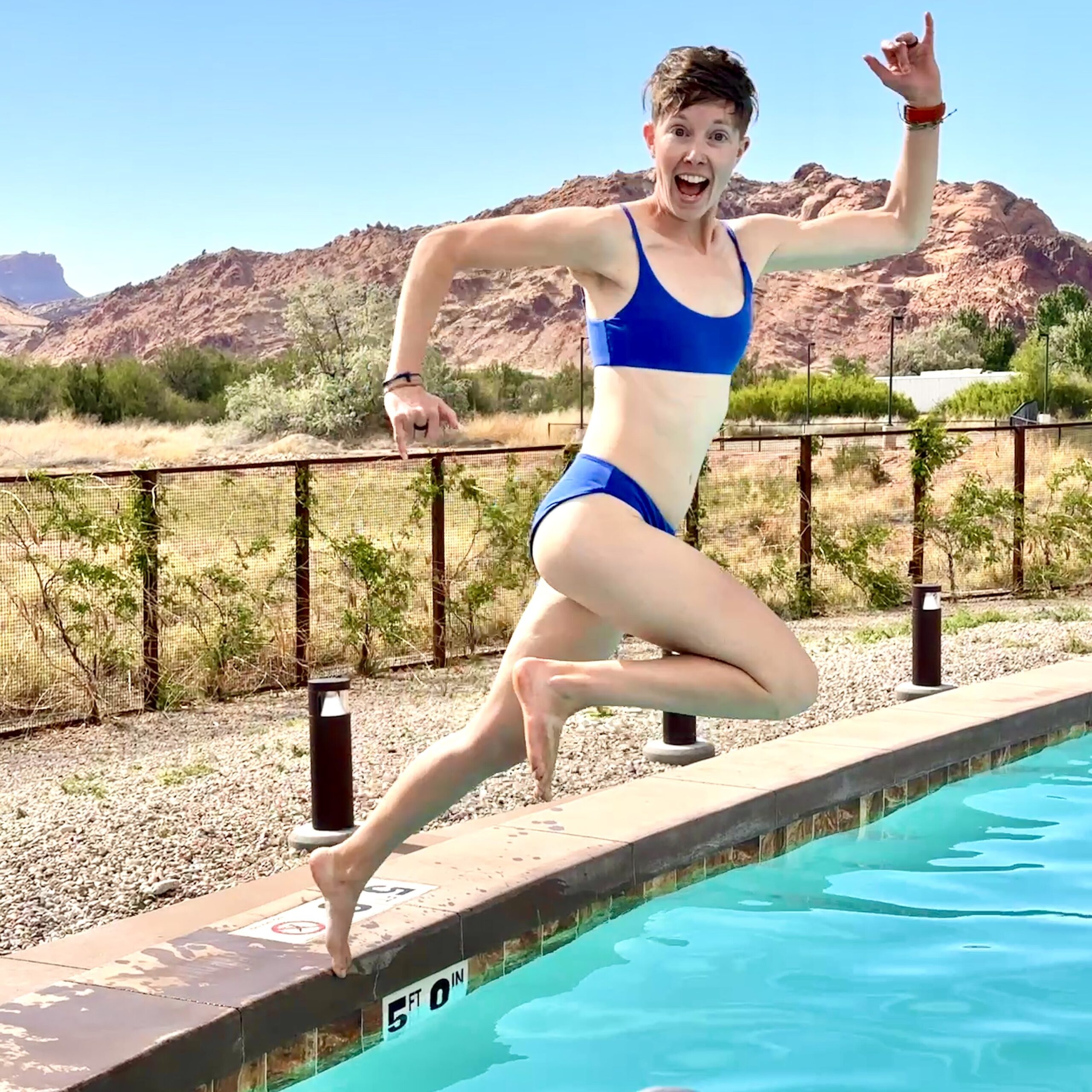 A woman jumps into a pool wearing the Carve Designs Escondido swimsuit top and St. Barth Swimsuit bottoms.