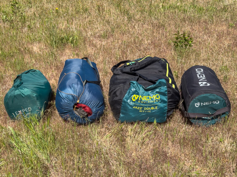Two double sleeping bags and double sleeping pads packed up and in a row.