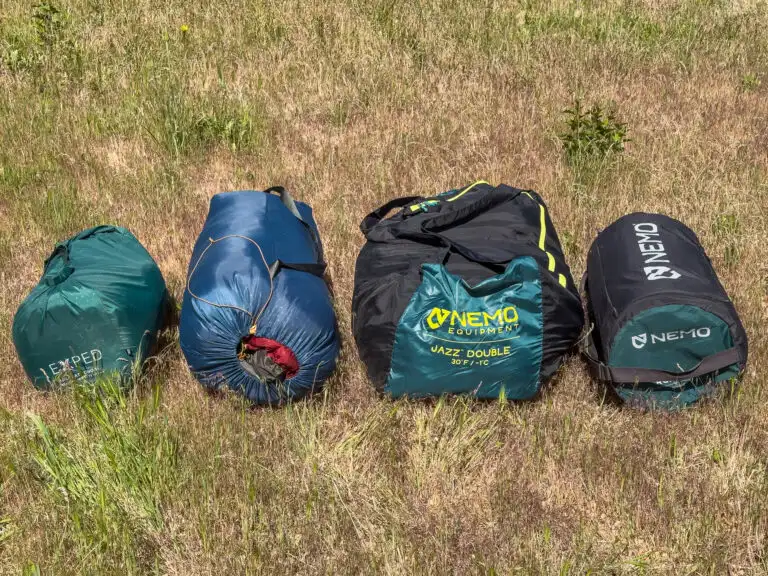 Two double sleeping bags and double sleeping pads packed up and in a row.