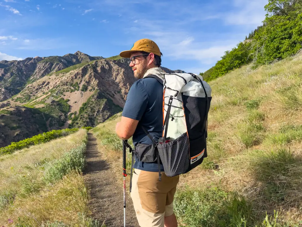 A man stands on a trail wearing the Hyperlite Mountain Gear Unbound 55 Backpack.