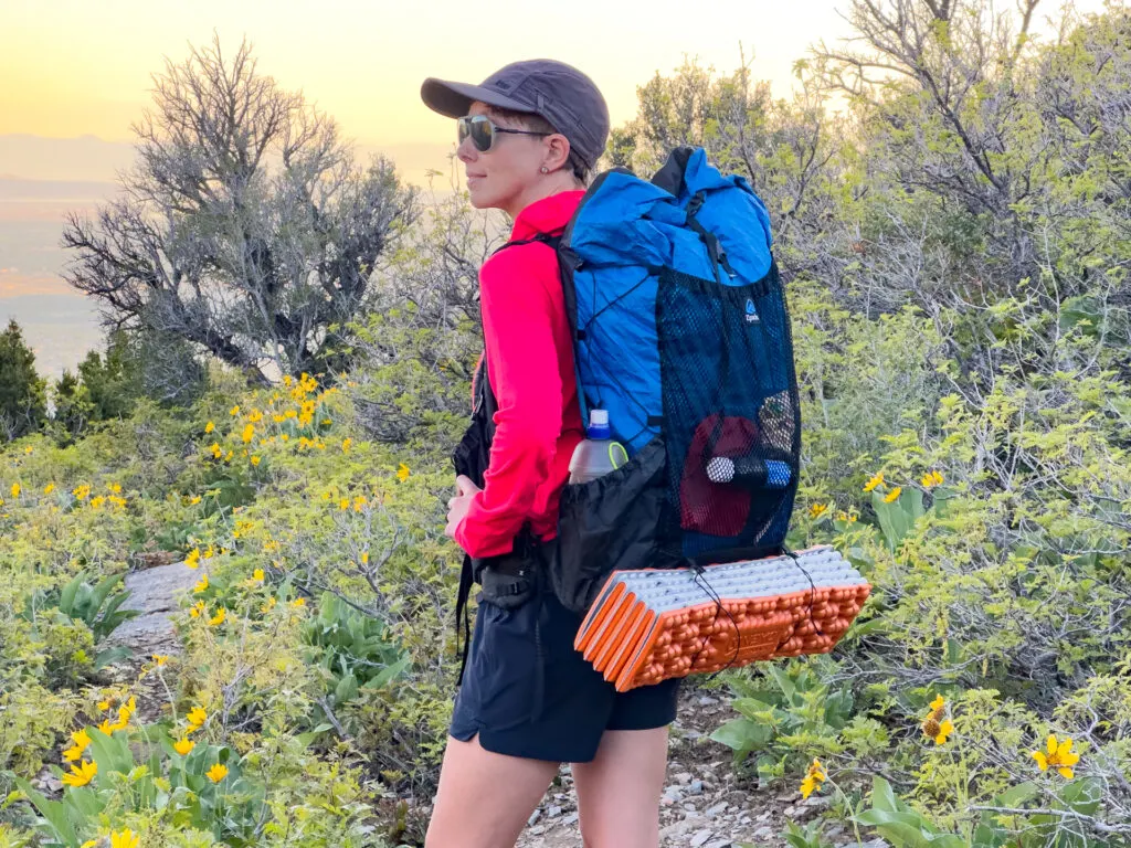 A woman stands on a trail wearing a Zpacks Backpack: the Super Nero Ultra 50.