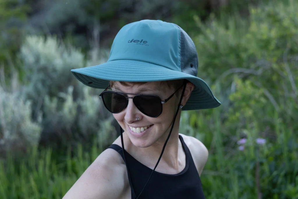 A woman wears the Ciele TRL Bucket Hat outdoors.
