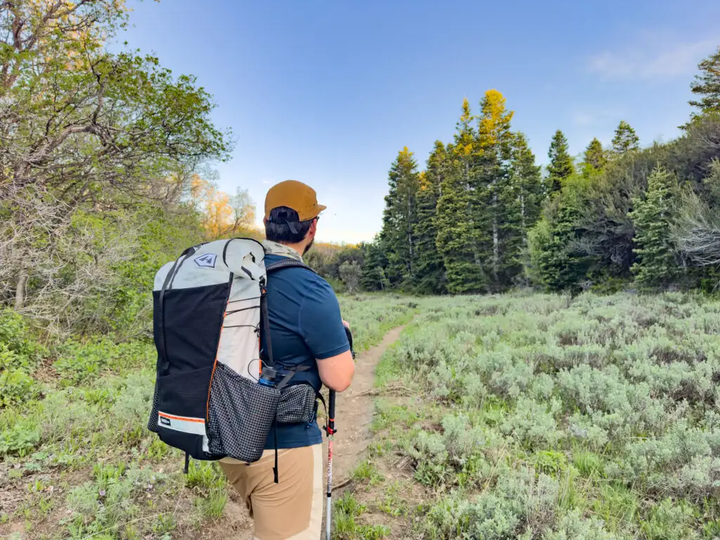 A man stands on a trail wearing the Hyperlite Mountain Gear Unbound 55 Backpack.