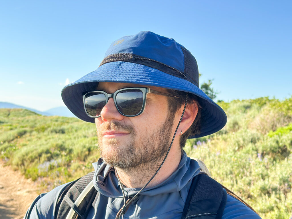 A man wears the Outdoor Research Odyssey Bucket Hat on a trail.
