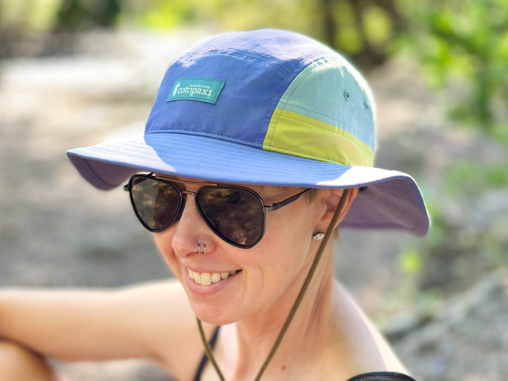 A woman wears the Cotopaxi Tech Bucket Hat outdoors.