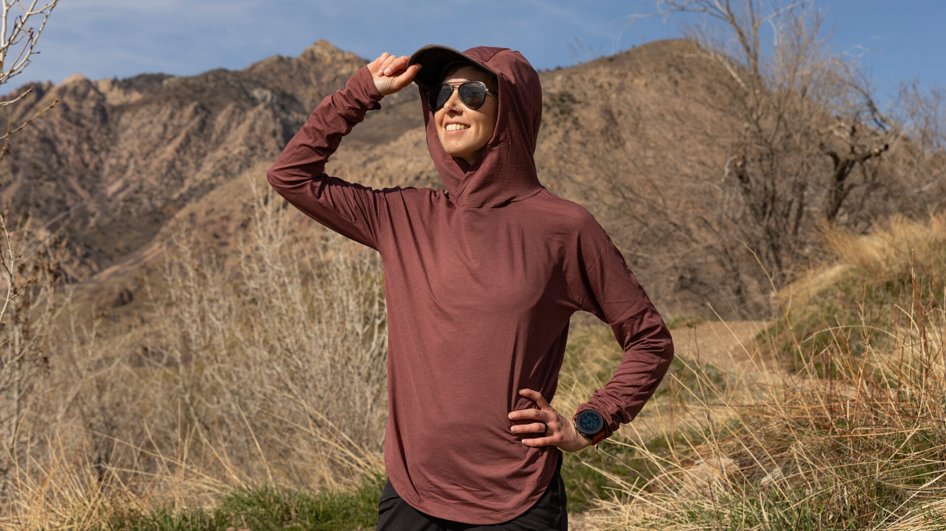 Woman wearing a REI Sahara sun hoodie in a desert mountain setting.