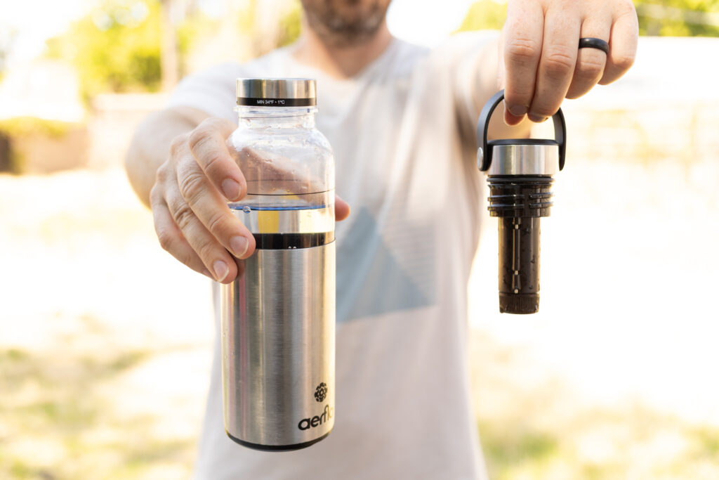 Hands hold the Aerflo bottle and lid separately.