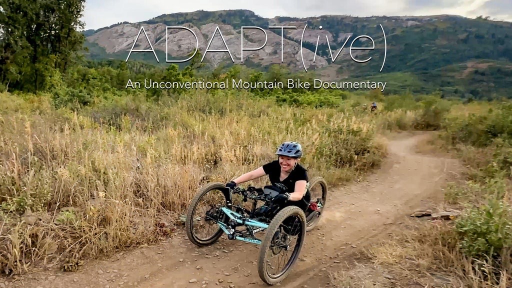 A woman rides an adaptive mountain bike on a trail.