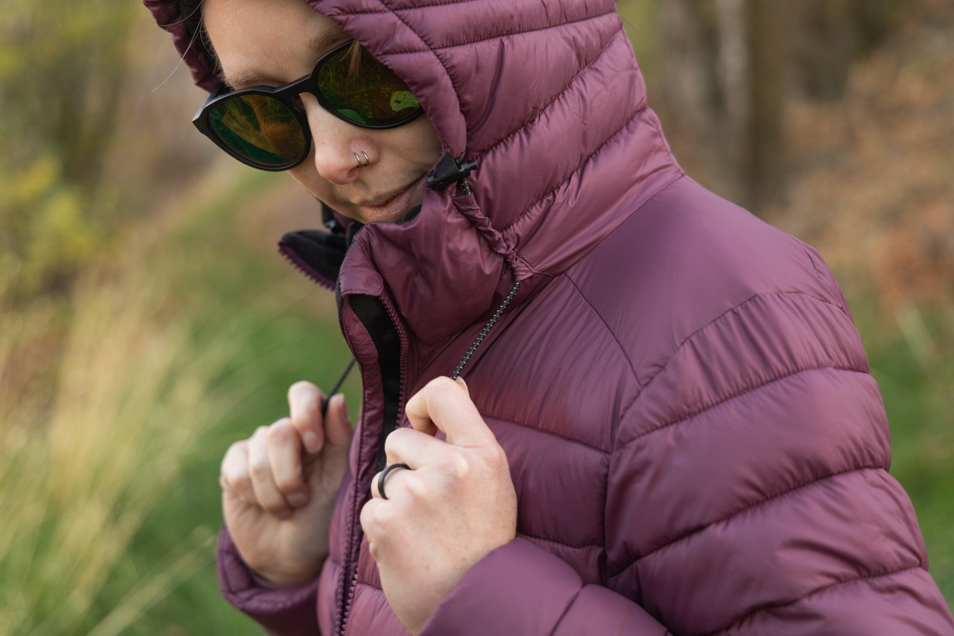 A woman pulls the hood bungees on a Finisterre Nimbus Jacket.