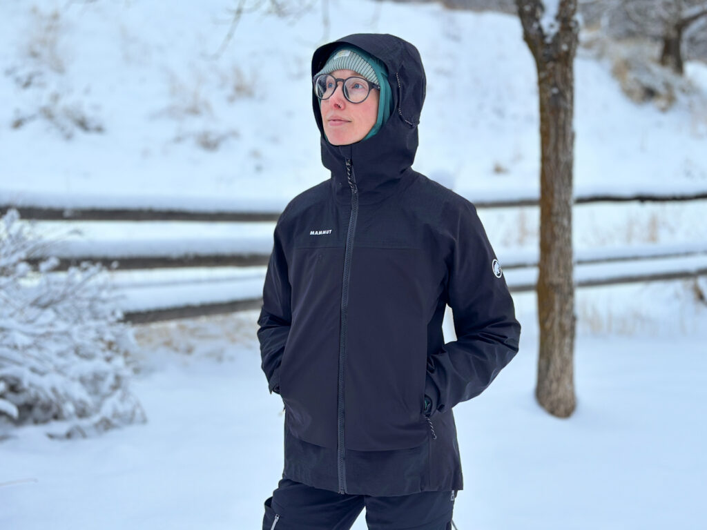 A woman wears a Mammut Duncan Guide HS shell jacket on a snowy trail.