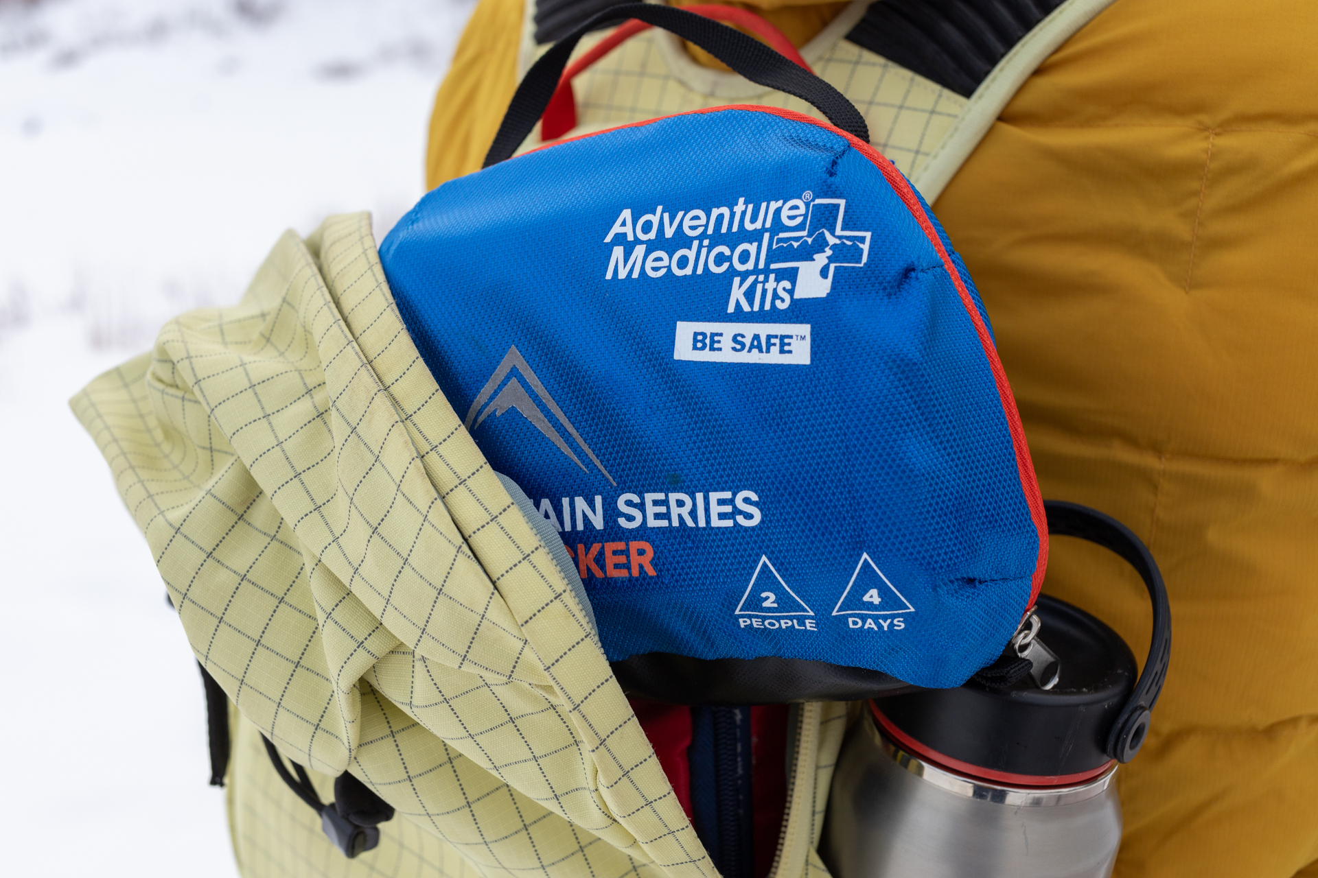A first aid kit sticks out of a backpack.
