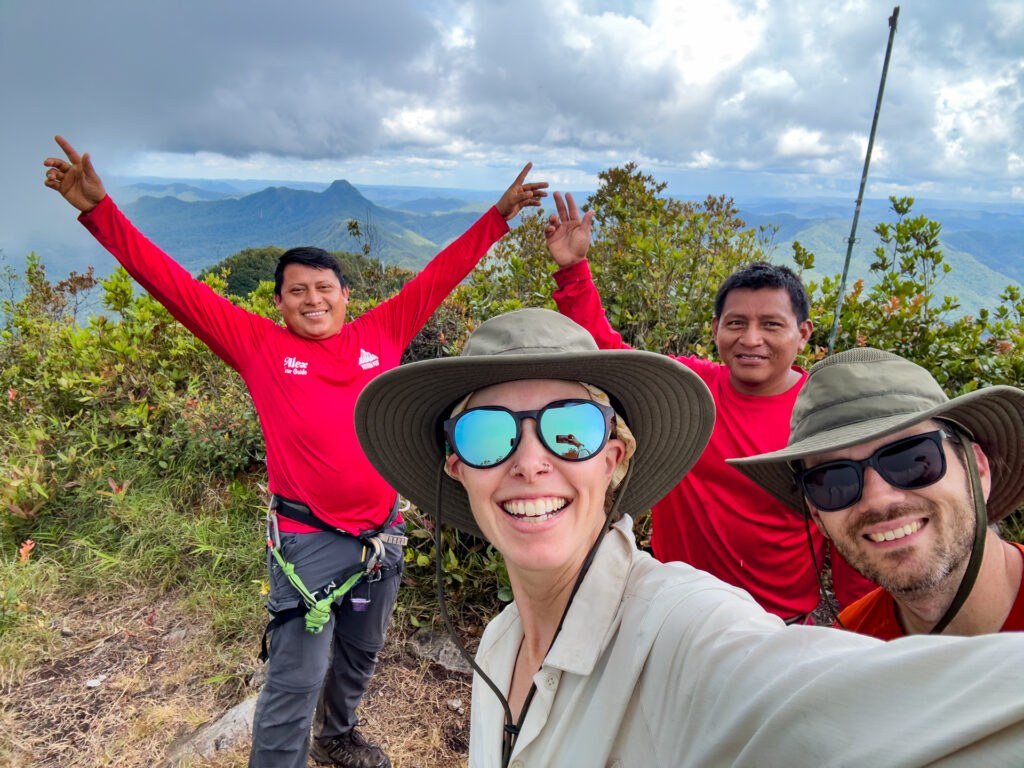 Four people smile at the summit of Victoria Peak.