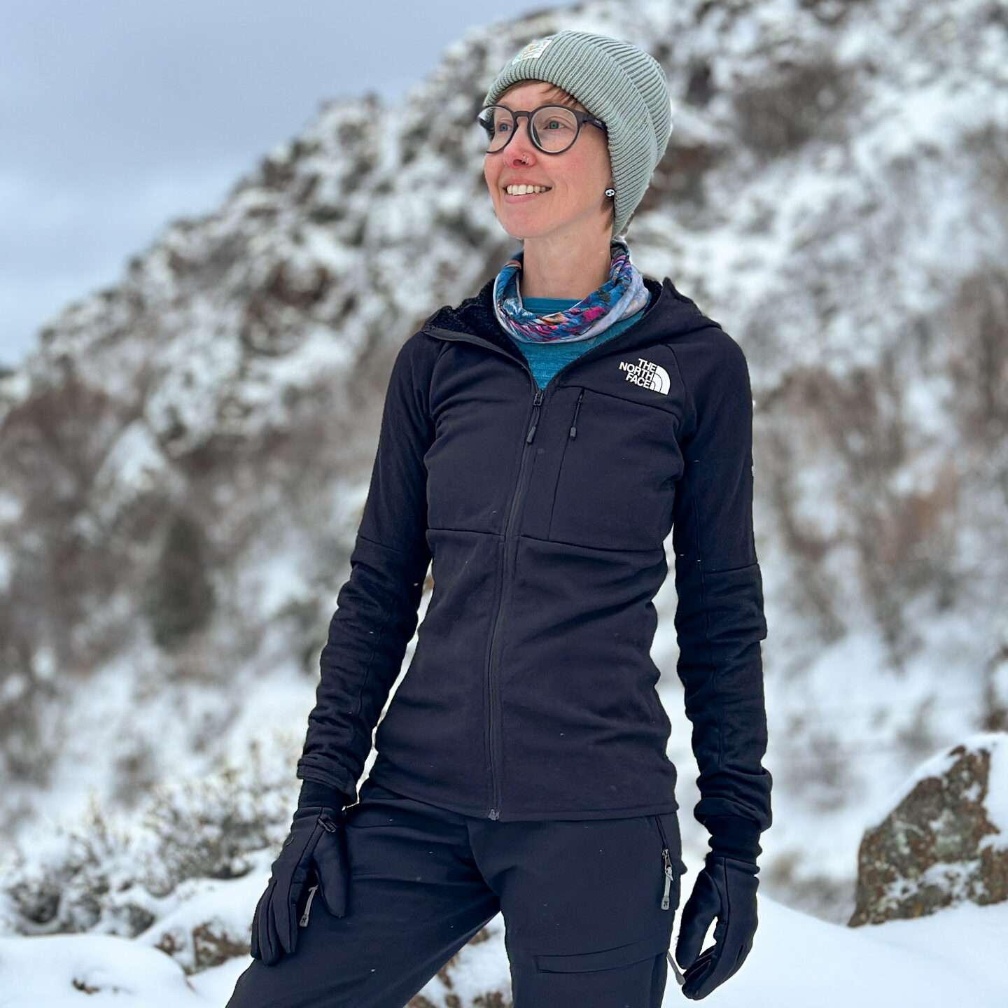 A woman stands in front of snowy mountains in a fitted The North Face FutureFleece.