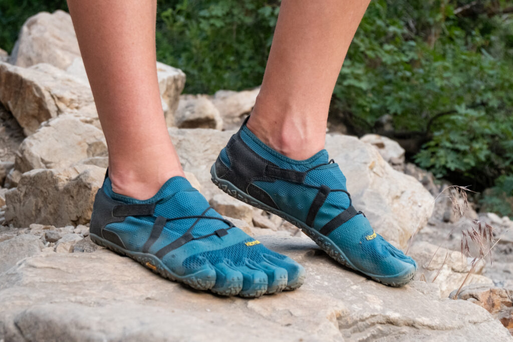 Feet walking on a dirt trail in Vibram Five Finger Spidrwalk shoes.