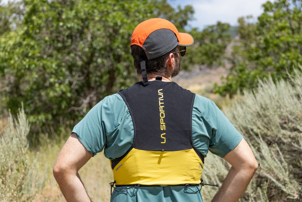 A man wears the La Sportiva Trail Vest 5L on a trail (back view).