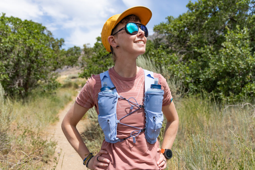 A woman wears a blue Deuter Traick 5 running vest.