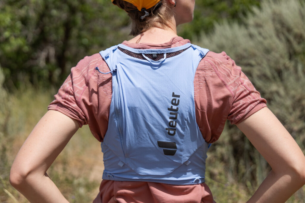 A woman wears a blue Deuter Traick 5 running vest (back view).