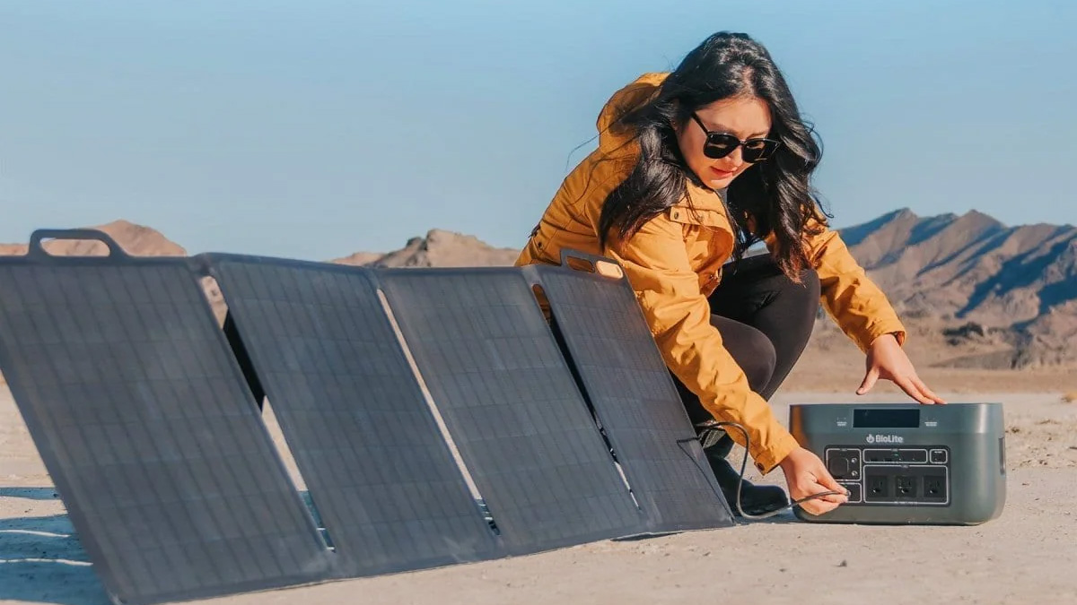 Woman plugging a Biolite power station into a SolarPanel 100